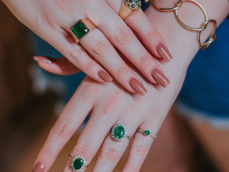 mano di donna con anelli con smeraldi
